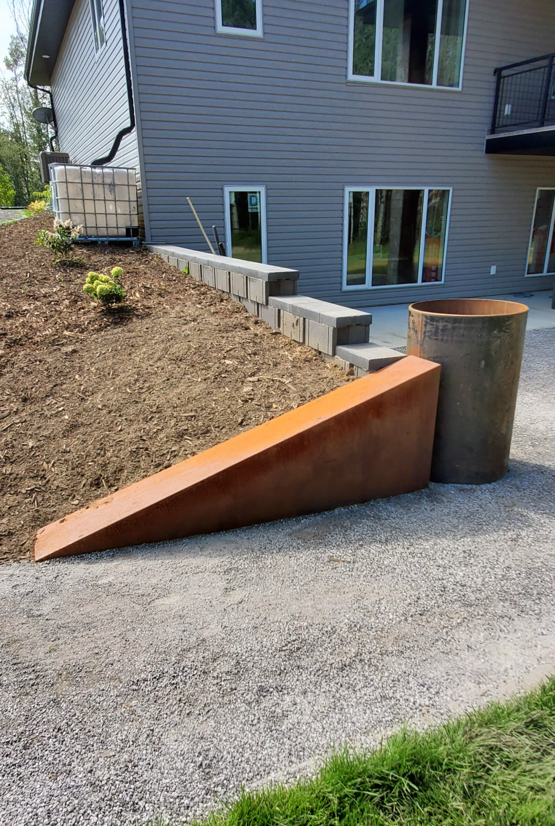 Custom built angled Corten steel retaining wall holding in fresh cedar mulch.