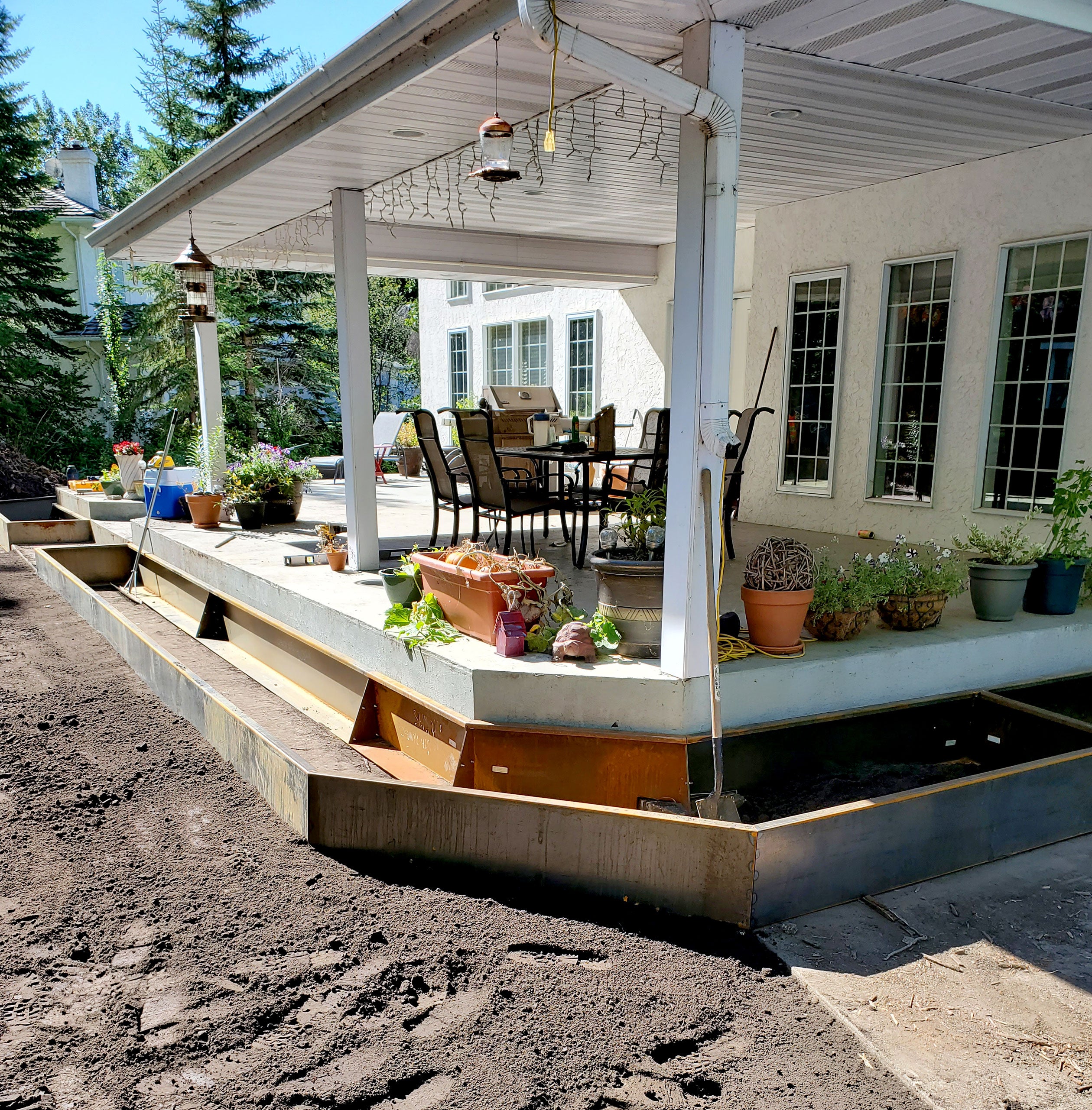 installation of custom Corten steel flowerbeds surrounding an existing deck