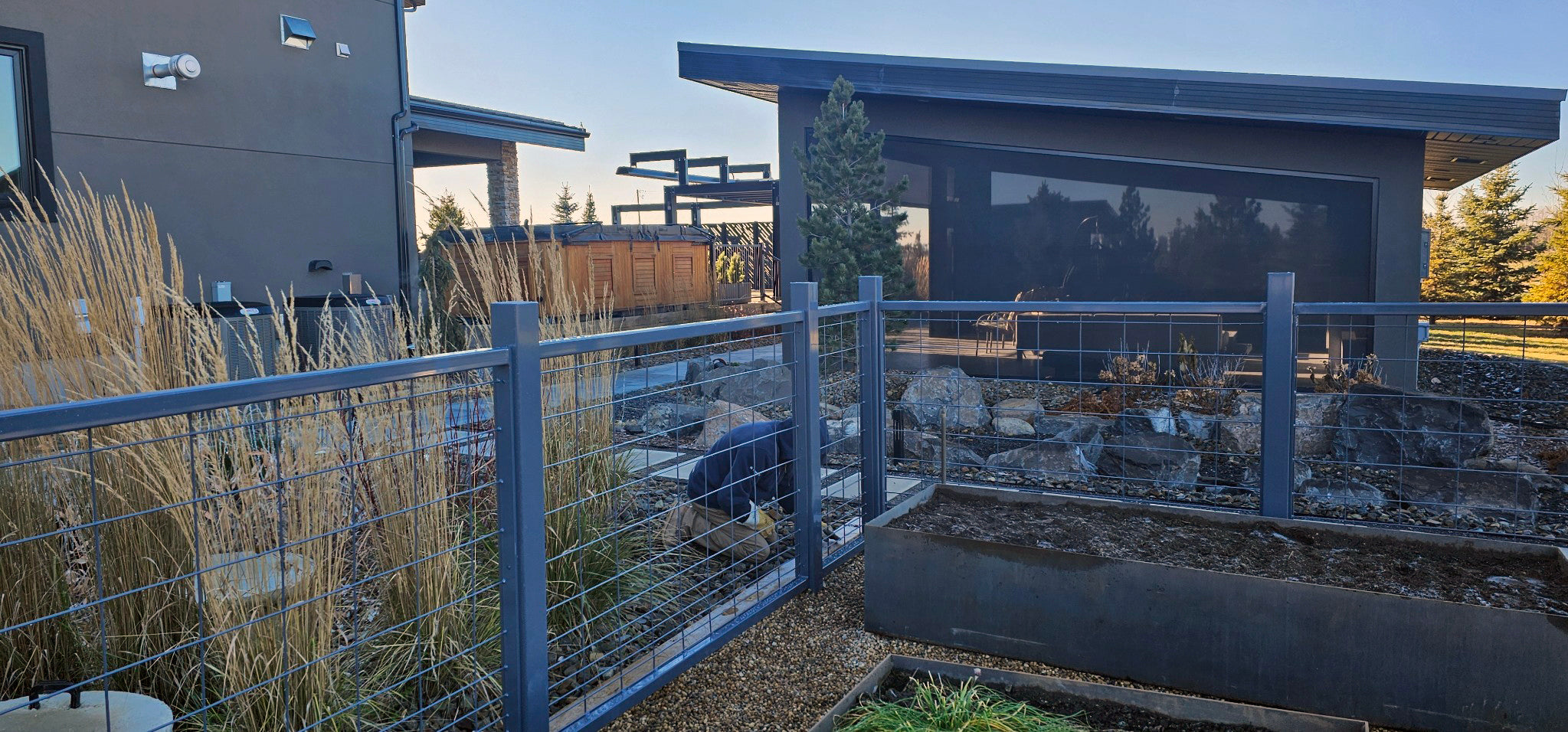 Custom built garden fencing coated to match house highlights, surrounding a rock pebble garden